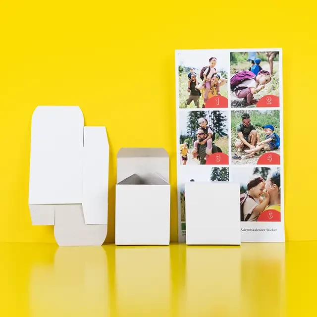 Offene Schachteln und Sticker-Set mit persönlichen Bildern zum Adventskalender selber machen.