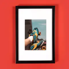Auf rotem Hintergrund hebt sich ein schwarzer Bilderrahmen mit einem sportlichen Rollschuhfoto stilvoll ab.