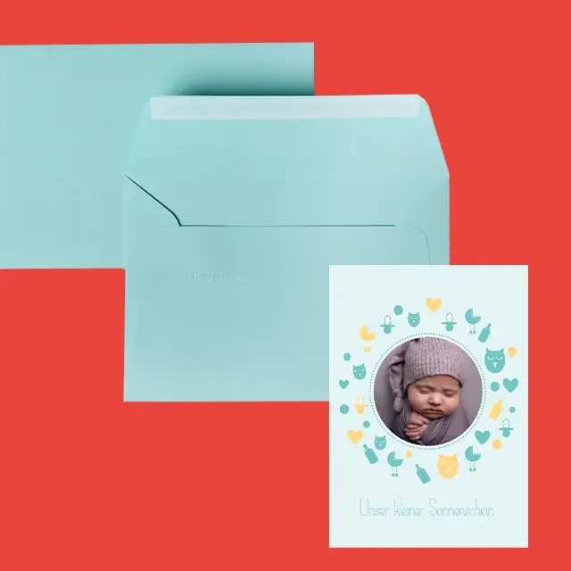Zwei mintfarbene Briefumschläge mit passender Karte zur Geburt liegt mit sichtbarer Klebefläche auf einem Tisch.