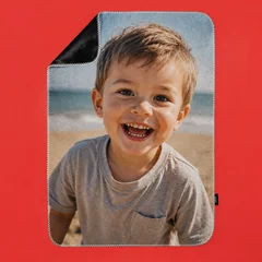 Fotodecke mit Kindermotiv am Strand und grauer Rückseite auf rotem Hintergrund.