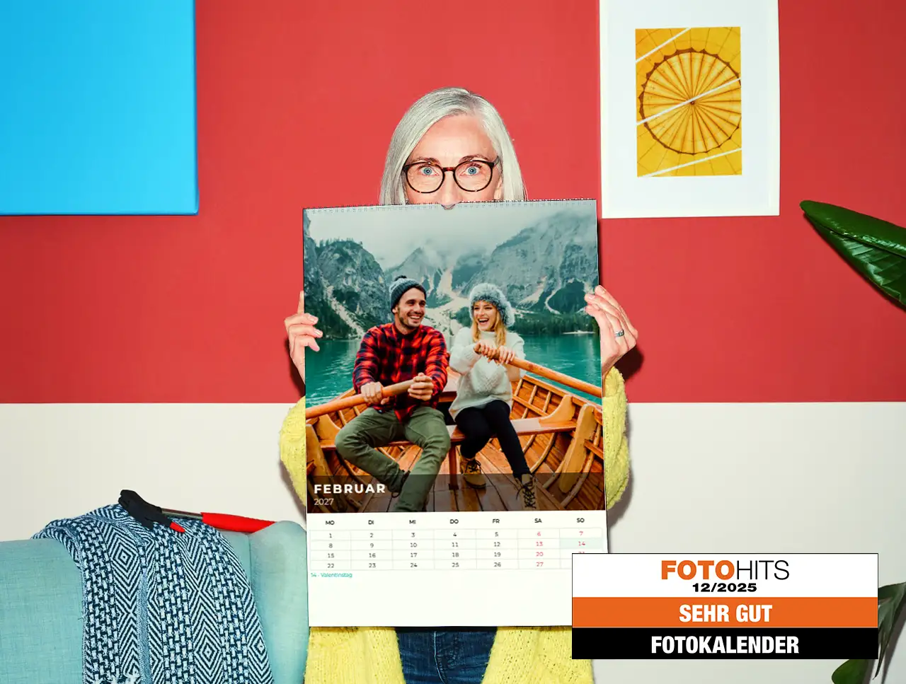 Frau hält einen personalisierten Fotokalender mit einem Paar im Ruderboot vor einer Bergkulisse.