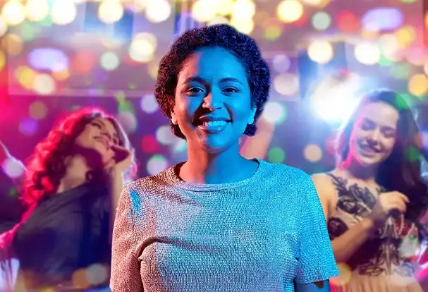 Eine Frau auf einer Party vor einem Lichtermeer. Nutze die gezielte Unschärfe auch für deine Frühlingsfotos.