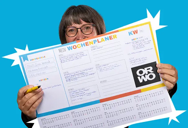 Frau mit Brille hält einen ORWO-Wochenplaner vor blauem Hintergrund. Entdecke Katjas Lieblingsprodukt, die ORWO Schreibtischunterlage.