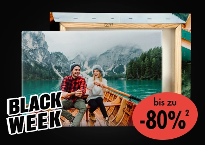 Paar sitzt lachend in einem Holzboot auf einem Bergsee, abgebildet auf einer Fotoleinwand – ORWO Black Week Angebot mit bis zu 80 % Rabatt.