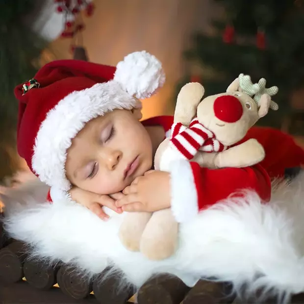Schlafendes Baby mit Plüschelch & roter Mütze – süße Inspiration für Weihnachtsfotos selber machen.