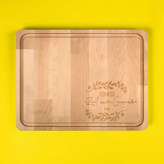 Gravierte Geschenke: Holzbrett mit personalisierter Gravur Ein elegantes Holzbrett, graviert mit dem Text „Zeit zum Genießen“ und einer filigranen Pflanzenranke, die den Schriftzug umrahmt. Dieses gravierte Geschenk ist perfekt für gemütliche Momente und eine besondere Erinnerung an den Hochzeitstag.