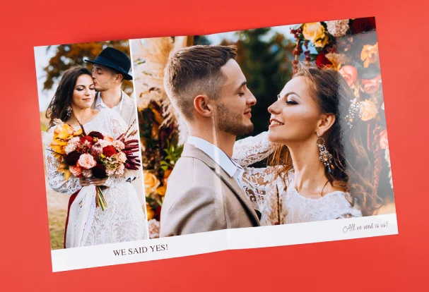 Aufgeschlagenes Echtfotobuch mit nahtloser Panoramabindung. Hochzeitspaar strahlt über die gesamte Buchmitte – kein Bildverlust dank Original Fotopapier.