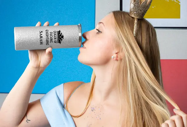 Eine Frau mit Krone genießt ihren silbernen Coffee-to-go-Becher voller funkelnder Freude.