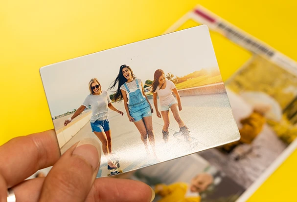 Hand hält matten Fotosticker mit Bild von Freundinnen auf dem Board. Perfekt für kreative Gestaltung und Scrapbooking.