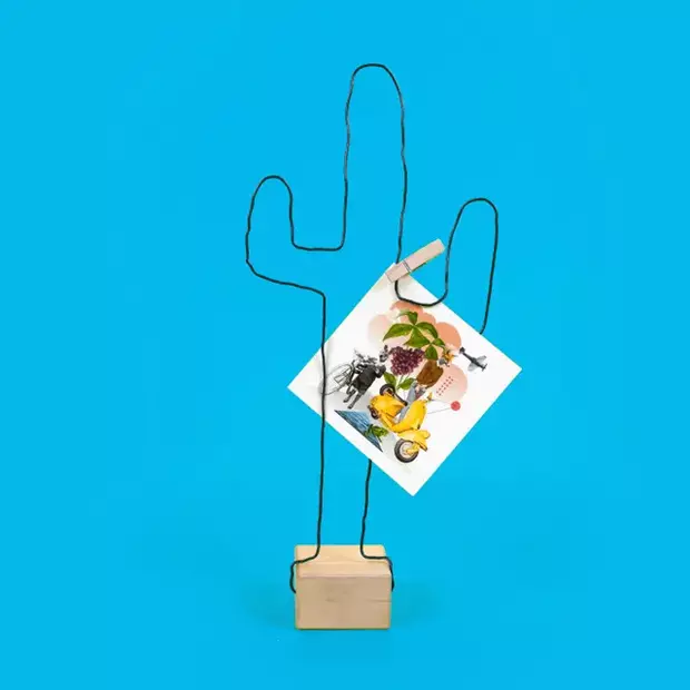 Fotohalter basteln – Kaktus-Form Der fertige Fotohalter in Form eines Kaktus ist bereit, ein Foto zu präsentieren. Ein quadratischer Fotoabzug wird mit einer kleinen Klammer am Drahtgestell befestigt. Die minimalistische Kaktusform und der Holzfuß geben dem Halter eine moderne und kreative Note. Eine tolle DIY-Idee für alle, die Fotohalter basteln möchten.