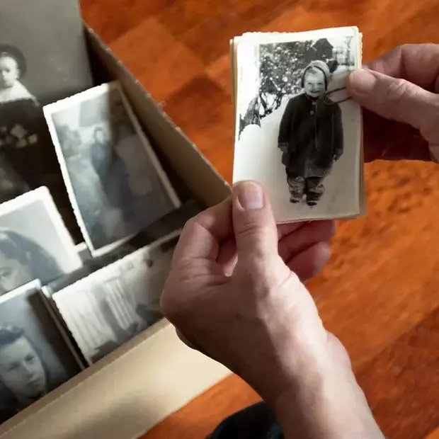  Ein Karton voller alter Schwarz-Weiß-Fotos – ein Händepaar blättert durch Erinnerungen. Emotionale Bild vom Bild-Momente.