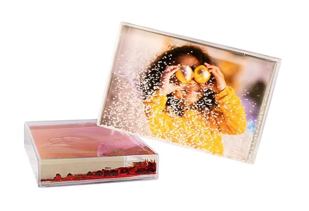 Transparenter Schüttelrahmen mit Foto eines lachenden Kindes und weißen Schneekügelchen als Effekt. ORWO Fotoprodukte zu Weihnachten.