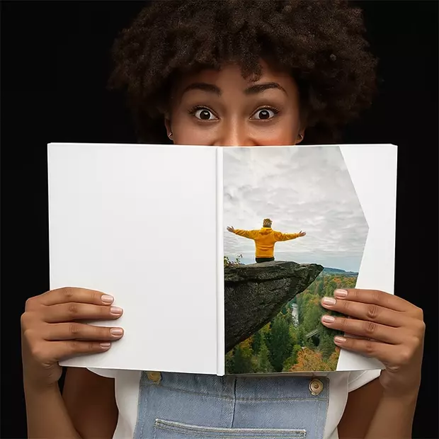Frau hält ein geöffnetes Fotobuch mit Naturmotiv und wirkt überrascht – Black Week Angebote bei ORWO.