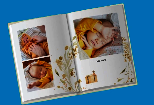 Aufgeschlagenes Hochzeitsfotobuch im sanften Design mit Babyfotos und floralen Elementen auf blauem Hintergrund