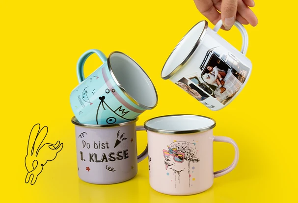 Oster Geschenkideen: Vier bunte Emailletassen mit individuellen Designs, darunter „Du bist 1. Klasse“ und eine Tasse mit einem coolen Lama-Motiv, auf einem gelben Hintergrund.