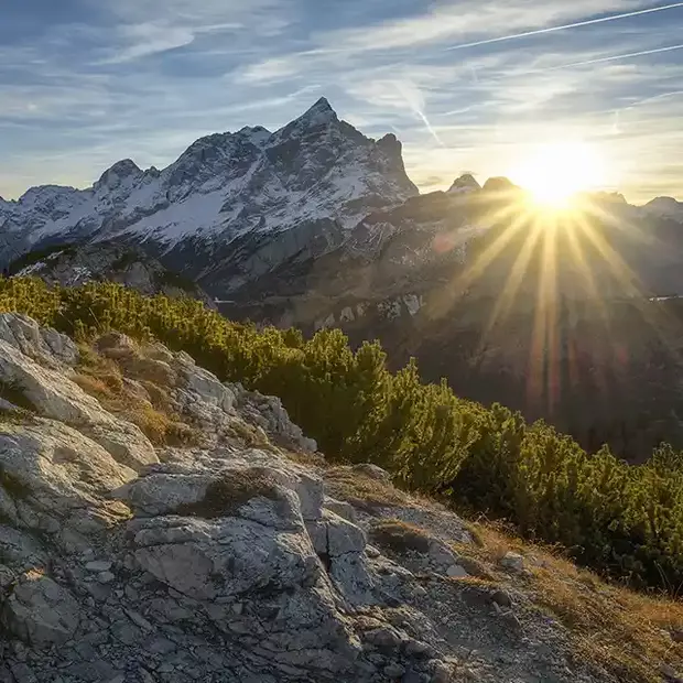 Gebirge Bilder: Sonnenaufgang über den Bergen Ein atemberaubender Sonnenaufgang hinter der Gipfelspitze eines Berges, der den Himmel in warmen Farben erleuchtet und die Berglandschaft in goldenes Licht taucht. Ein faszinierendes Bild der Natur, das die Ruhe und Majestät des Gebirges widerspiegelt.