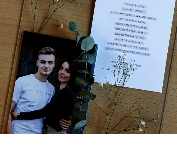 Paarfoto im schlichten Bilderrahmen neben Liebesgedicht und Trockenblumen – romantische Fotoidee als individuelles Valentinstagsgeschenk