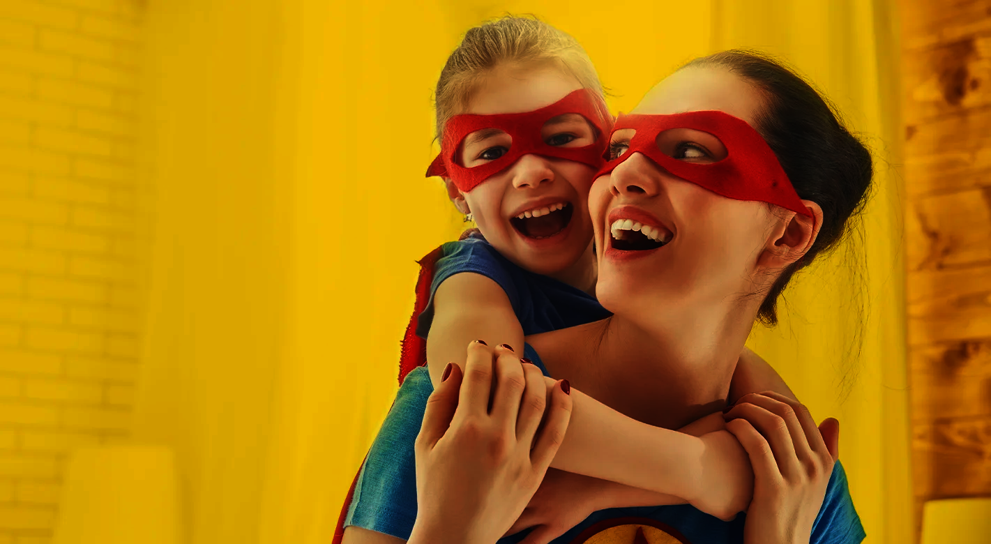 Mutter und Kind mit roten Masken lachen gemeinsam und spielen Superhelden als emotionales Motiv für starke Bindung und kreative Fotogeschenke zum Muttertag