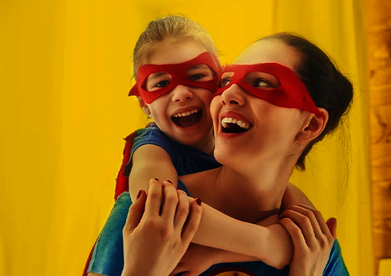 Mutter und Kind mit roten Masken lachen gemeinsam und spielen Superhelden als inspirierende Szene für kreative Fotogeschenke Ideen zum Muttertag mit persönlicher Bedeutung