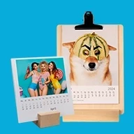 Zwei einzigartige Tischkalender: Klemmbrett aus Holz mit dem witzigen Motiv – Hund mit Melonenhelm. Der andere präsentiert 13 Kalenderblätter stilvoll auf einem Holzfuß.
