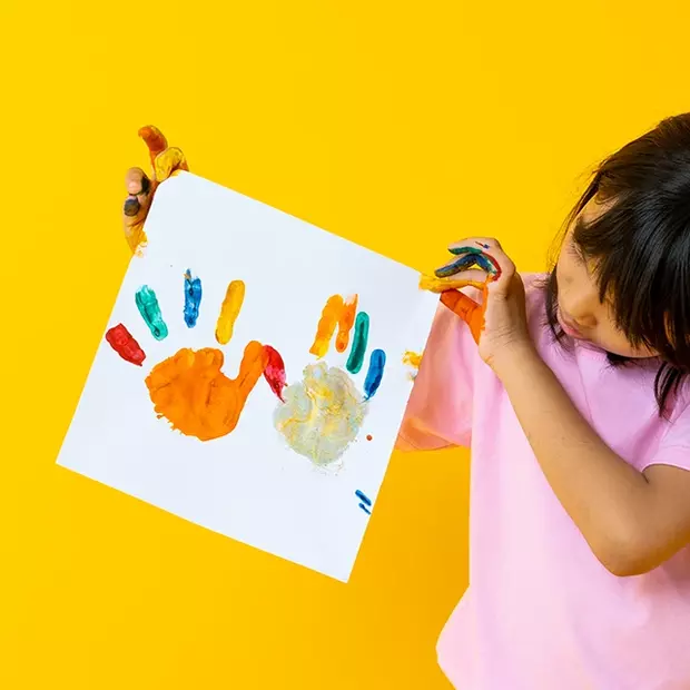 Kalender mit Kinderbildern: Stolzes Kind mit buntem Kunstwerk Ein Kind hält stolz sein selbst gestaltetes Bild in die Kamera – ein Kalender mit Kinderbildern. Auf weißem Papier sind bunte Handabdrücke zu sehen. Die Hände des Kindes sind noch voller Farbe.