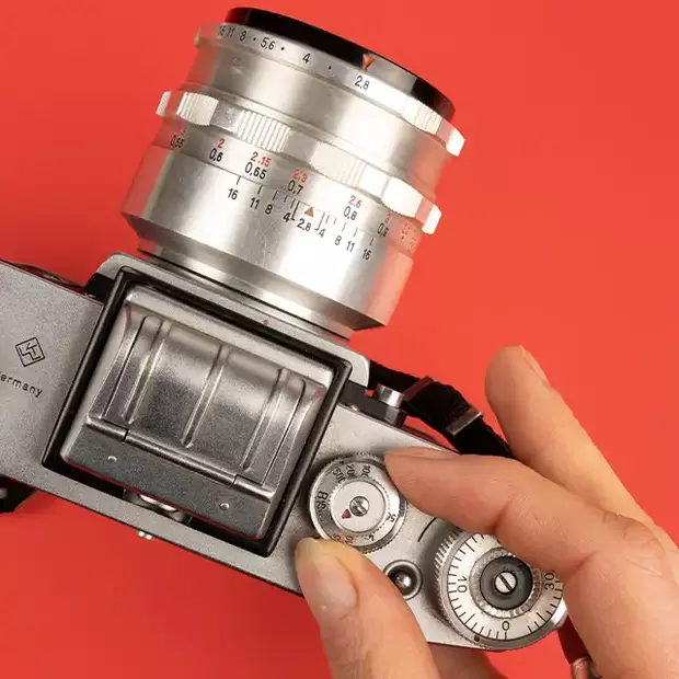 Filmempfindlichkeit einstellen: Perfekte Aufnahmen mit Analogkameras Eine Person stellt die Filmempfindlichkeit an einer Analogkamera ein, um perfekte Aufnahmen zu gewährleisten.