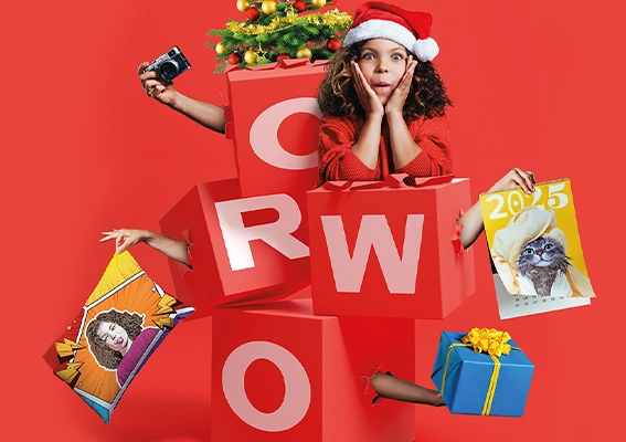 Wackelnde Würfel mit dem Schriftzug ORWO bringen weihnachtliche Freude: Tannenbäumchen, ein Fotokissen, ein Kalender und ein kleines Mädchen mit Weihnachtsmütze und staunendem Blick schauen aus den Würfeln hervor 