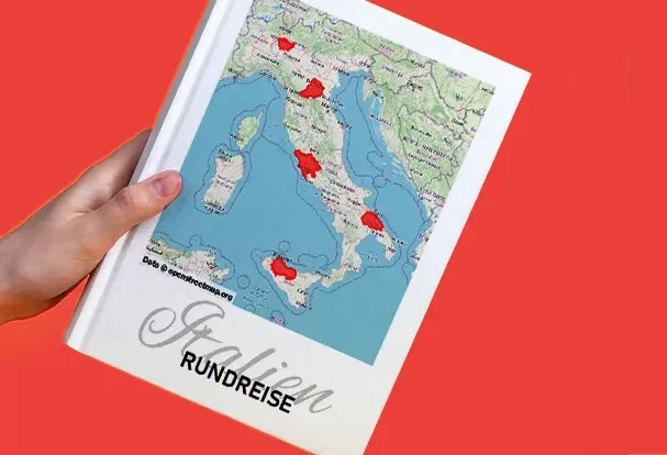 Ein Reise-Fotobuch mit Landkarte von Italien und markierten Stationen dient als kreatives Cover-Design.