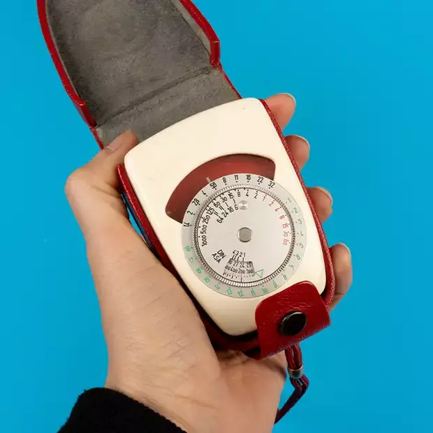 Ein alter Belichtungsmesser, von einer Hand bedient, trägt Spuren vergangener Nutzung und strahlt den Charme vergangener Fotografiezeiten aus.