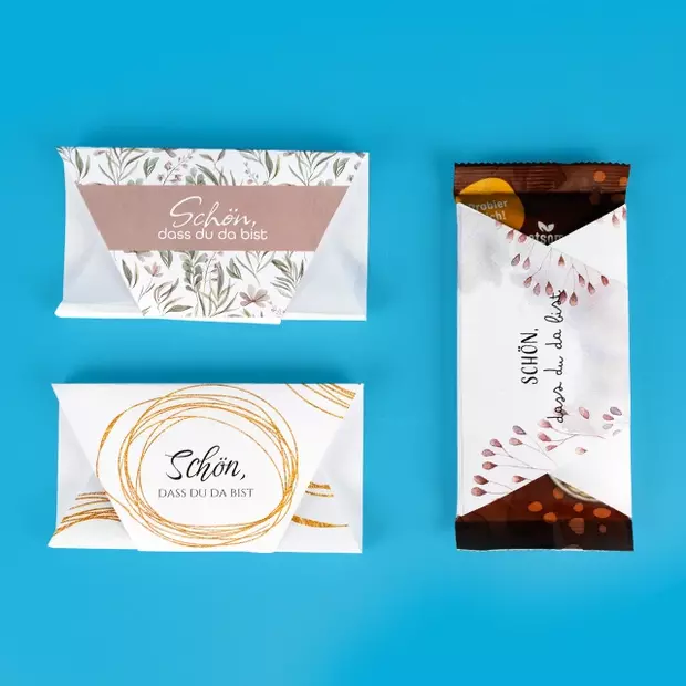 Schokolade verpacken als Gastgeschenk zur Hochzeit. Die drei Schokoladen Banderolen verpacken deine kleinen Gastgeschenke zur Hochzeit. Der Schriftzug „Schön, dass du da bist“ ist auf allen Designs vorhanden. Drei Designs: von schlicht modern bis romantisch verspielt.