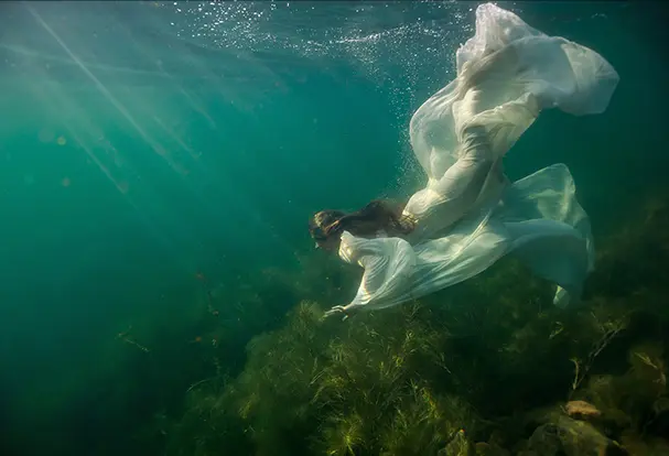 Unterwasseraufnahme einer Frau in weißem Kleid. 10 Tipps für atemberaubende Unterwasserfotos gibt’s von ORWO!