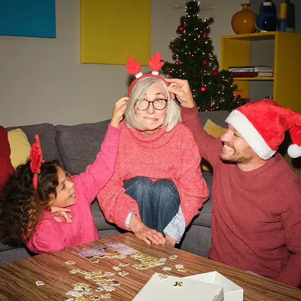 Familienspaß in der Weihnachtszeit: Oma, Papa und Kind genießen gemeinsam eine gemütliche Puzzlerunde in festlicher Atmosphäre.