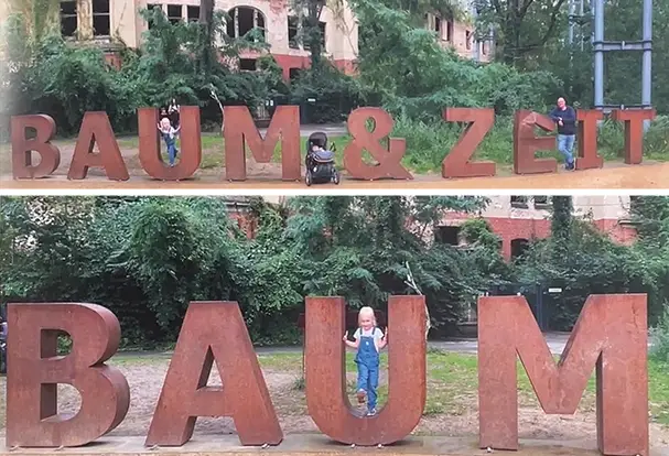 Große Metallbuchstaben 'BAUM & ZEIT' und 'BAUM' mit Menschen davor. Wie einzigartige Erinnerungsfotos auf Familientrips entstehen, erfährst du bei ORWO. 