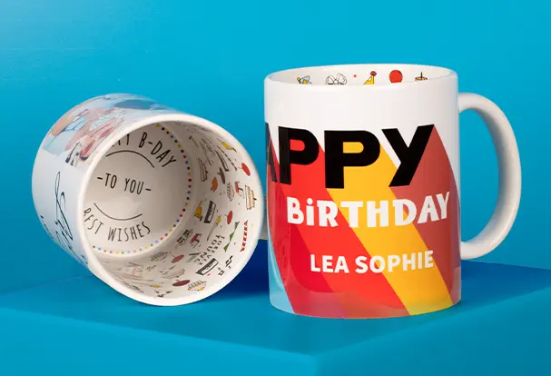 Zwei personalisierte Geburtstags-Tassen: Eine zeigt den individuellen Druck, die andere den Innendruck mit „Happy Birthday to you. Best wishes“. Dazu ein stilvoller Geburtstagskalender aus Holz – das perfekte Geschenk-Kombipaket.