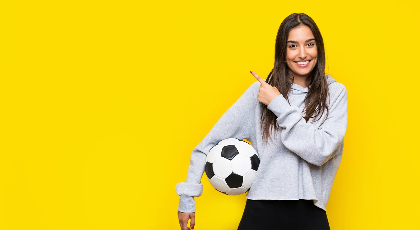 strahlende Frau mit Fußball unter ihrem Arm