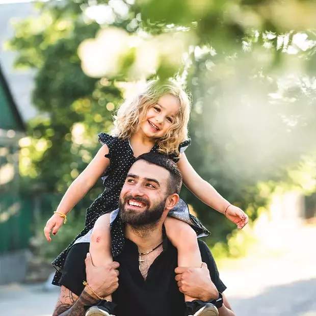 Frühlingshafter Bokeh-Effekt: Probiere es auch bei Tageslicht Bokeh-Effekt geht auch im Tageslicht. Der Vater trägt seine kleine Tochter huckepack, im grünen Hintergrund verschmelzen Büsche und Bäume zu einer magischen Einheit.