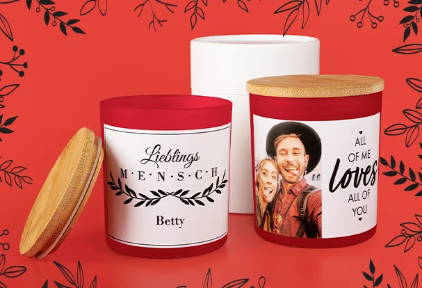 Personalisierte Weihnachtsgeschenke: Duftkerzen im Glas Zwei stilvolle Duftkerzen im Glas mit Holzdeckel und individuell bedrucktem Etikett: Ein Design trägt die Aufschrift „Lieblingsmensch“, das andere zeigt „All of me loves all of you“ mit einem romantischen Bild eines Paares. Diese Fotogeschenke Weihnachten verbinden persönliche Botschaften mit gemütlichem Flair.