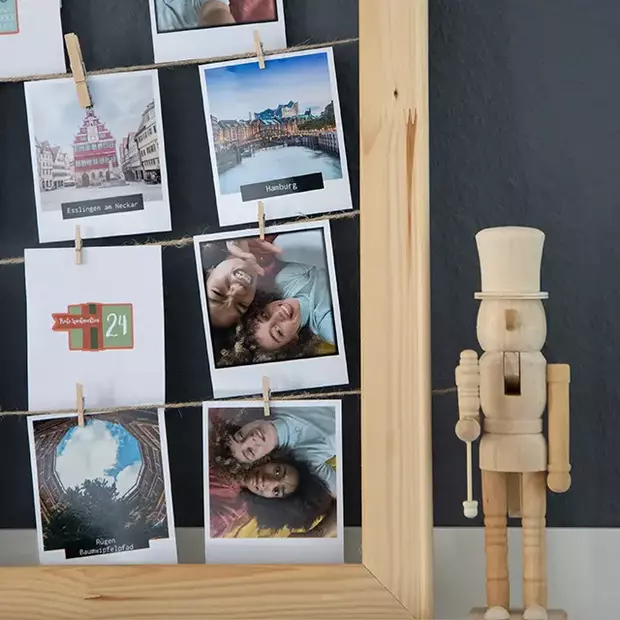 Fertiger DIY Weihnachtskalender mit Weihnachtsdeko Nahaufnahme eines fertigen DIY Weihnachtskalenders auf einem Regal. Der Kalender ist liebevoll mit Fotos und Zahlen gestaltet. Daneben steht eine festliche Weihnachtsdekoration, ein Nussknacker, der dem Bild eine nostalgische Atmosphäre verleiht.