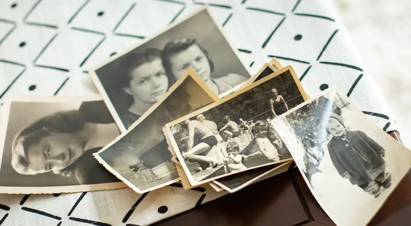 Bild vom Bild – historische Familienfotos im klassischen Vintage-Stil mit gezacktem Fotopapierrand Mehrere alte Schwarz-Weiß-Fotografien mit gezacktem Rand liegen auf einem Tisch. Familienmomente aus vergangenen Zeiten – ein echtes Bild vom Bild.