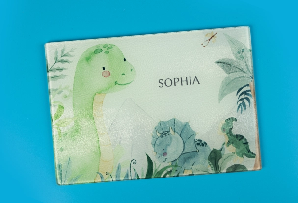 Kalender mit Kinderbildern: Individuelles Schneidebrett Ein Schneidebrett aus Glas, bedruckt mit bunten Dinosauriern und weiteren fantasievollen Motiven. Eine kreative Geschenkidee mit persönlicher Note.