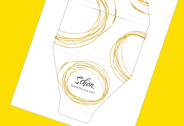 DIY-Bastelbogen „Elegant und zeitlos“ – Mit dem Design kannst du nicht nur Schokolade verpacken. Dieser Bastelbogen besticht mit seiner Einfachheit: Weißer Hintergrund, goldene, ineinander geschlungene Kreise und die schwarze Aufschrift „Schön, dass du da bist“ kann deine Schokolade elegant und zeitlos verpacken.