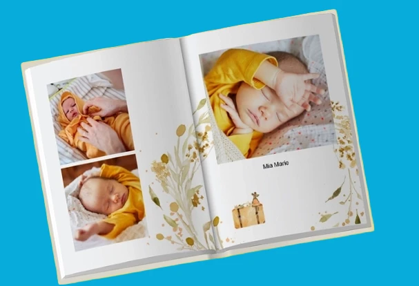 Mit individuellen Layouts und persönlichen Bildern gestalten Aufgeschlagenes Hochzeitsfotobuch im sanften Design mit Babyfotos und floralen Elementen auf blauem Hintergrund