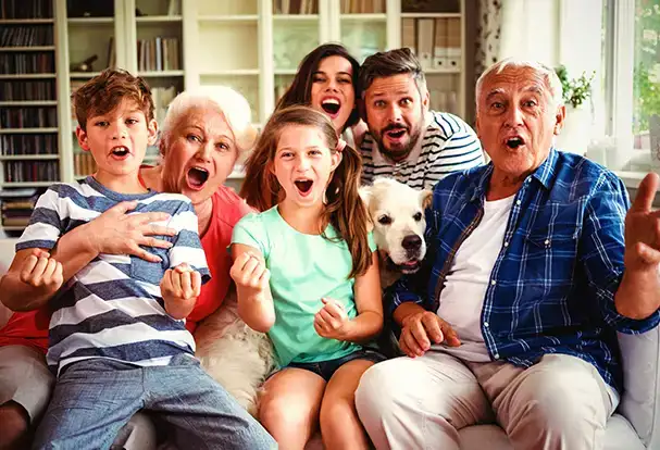 Frühlingsfotos mit der ganzen Familie: Hol dir Tipps Eltern, Großeltern, zwei Kinder und ein Hund schauen mit offenen Mündern in die Kamera. Frühlingsfotos kannst du auch mit deiner Family machen.
