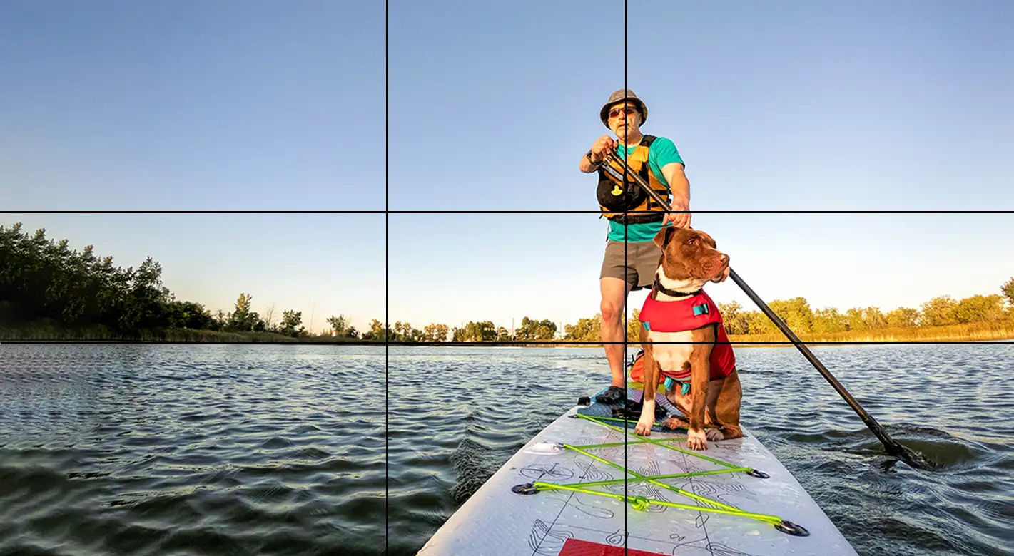 Goldener Schnitt: Alles, was du wissen musst Bildanordnung nach dem Raster des goldenen Schnitts: Fotografie von einem Mann und einem Hund auf einem SUP.
