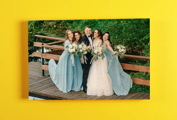 Fotogeschenke Hochzeit: Gruppenbild auf Holzdruck Ein wunderschönes Gruppenbild des Brautpaares mit den Brautjungfern, aufgenommen auf einer Brücke. Dieses besondere Foto ist auf hochwertigem Holz gedruckt und eignet sich perfekt als dekoratives Fotogeschenk, das die Erinnerungen an den Hochzeitstag für immer bewahrt.