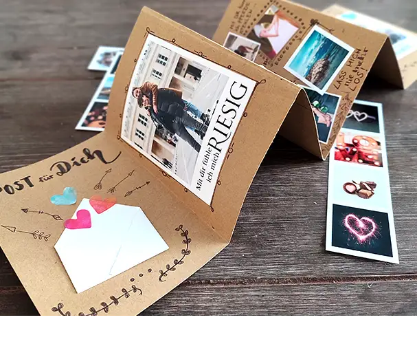 DIY Leporello als persönliches Fotogeschenk DIY Leporello Fotogeschenk mit persönlichen Fotos, handgeschriebenen Botschaften und Herzmotiven – kreatisches Valentinstagsgeschenk aus Papier auf Holztisch