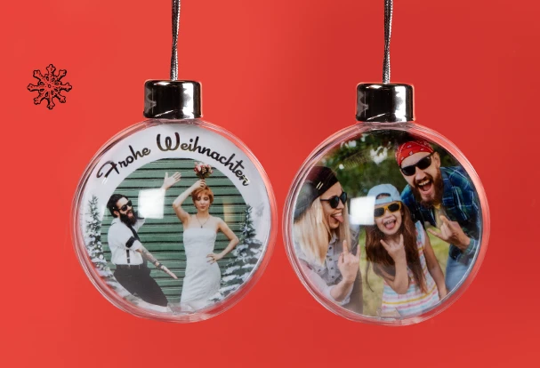 Fotogeschenke Weihnachten – personalisierte Christbaumkugeln mit eigenem Foto Zwei personalisierte Fotogeschenke zu Weihnachten in Form von transparenten Christbaumkugeln mit individuellen Fotos und Aufschrift „Frohe Weihnachten“.