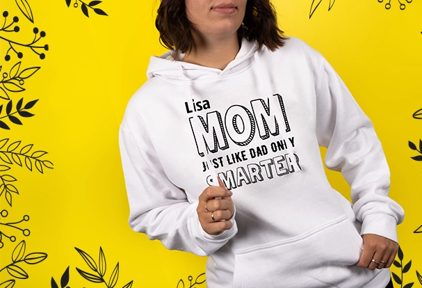 Personalisierte Weihnachtsgeschenke: Hoodie mit individuellem Print Eine junge Frau trägt einen weißen Hoodie mit personalisiertem Print. Der Text „Mom, just like dad, only smarter“ wird durch den Namen der Mutter ergänzt. Ein stilvolles und humorvolles Fotogeschenk Weihnachten, das Individualität und Persönlichkeit perfekt kombiniert.