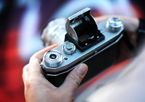 Eine Person nutzt eine alte analoge Kamera, während sie sich auf die Fotografie konzentriert – ein authentischer Moment mit klassischer Technik aus der Welt der Fotoprodukte.