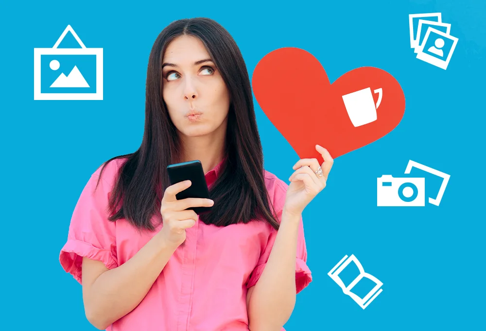 Frau in pinkem Shirt hält ein Smartphone und ein rotes Herzsymbol in der Hand, umgeben von Icons für Bilder, Kamera, Tasse und Fotobuch – kreative Fotoprodukte und Fotogeschenke zum Valentinstag